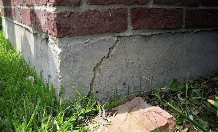 Fissure dans le coin d’une fondation en béton sous un mur de brique